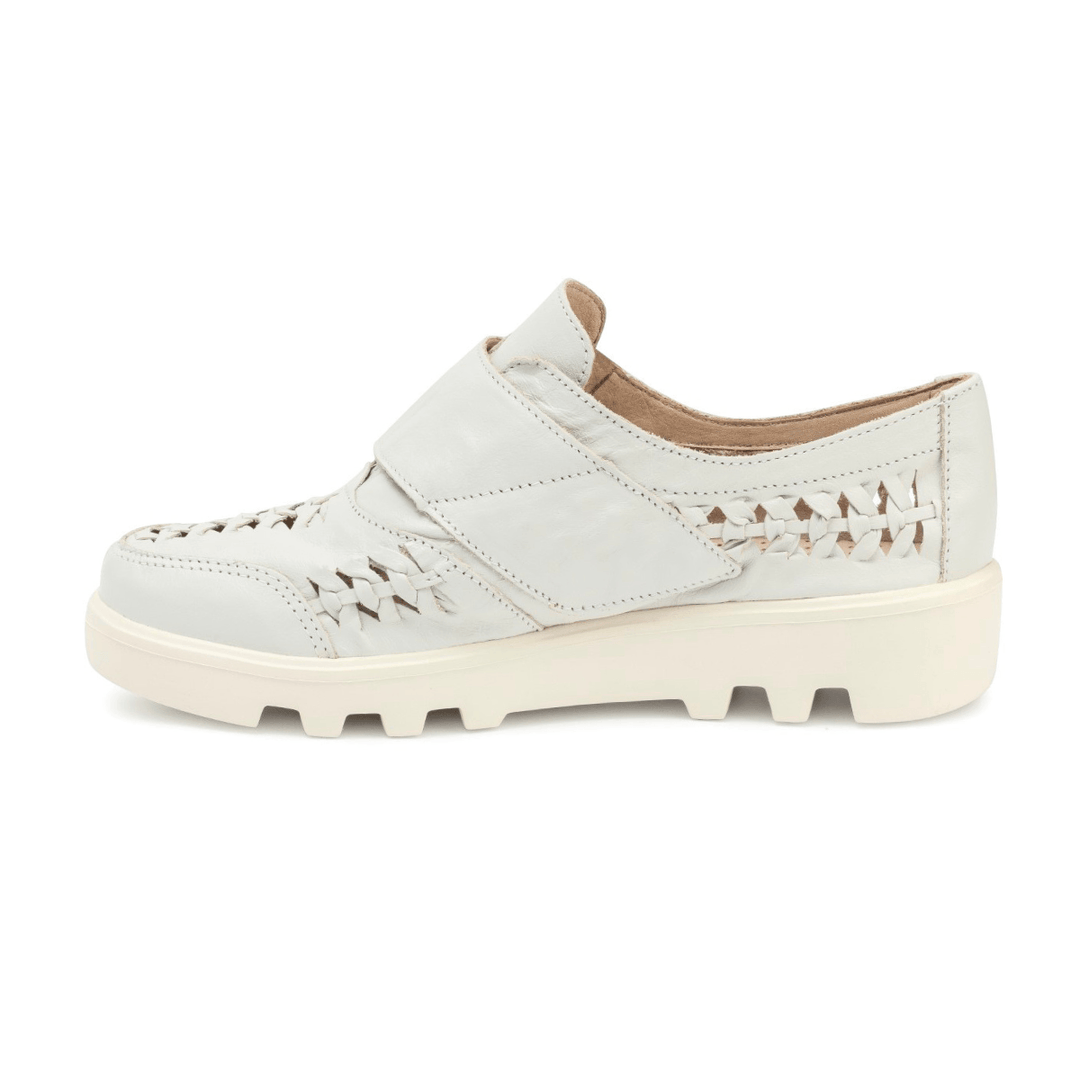 Sapato casual feminino em couro nude com recortes vazados, fechamento em velcro e solado tratorado off-white em fundo branco.